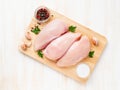 Raw chicken breast fillet with spices on wooden board on white wooden table, top view Royalty Free Stock Photo