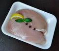 Raw chicken breast fillets skinned with basil leaves, lemon and pepper