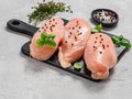 Raw chicken breast with fresh basil on black cuttingboard over cement background Royalty Free Stock Photo