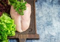 Raw chicken breast, vegetables and green salad on chopping board.