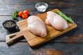 Raw chicken breasts and spices on wooden cutting board on old dark table side view Royalty Free Stock Photo