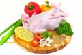 Raw chicken on a cutting board with garnished vegetables with a white background Royalty Free Stock Photo