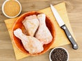 Raw chicken drumsticks in a bamboo bowl, knife, masala, black pepper Royalty Free Stock Photo