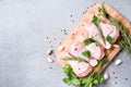 Raw chicken drumsticks with seasonings on wooden cutting board over gray concrete background Royalty Free Stock Photo