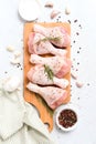 Raw chicken drumsticks with seasonings on wooden cutting board over white concrete table background with copy space Royalty Free Stock Photo