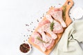 Raw chicken drumsticks with seasonings on wooden cutting board over white concrete table background with copy space Royalty Free Stock Photo