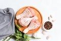 Raw chicken drumsticks with seasonings on wooden plate over white concrete background Royalty Free Stock Photo