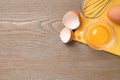 Raw chicken egg, bowl with yolk and whisk on wooden table, flat lay. Space for text Royalty Free Stock Photo