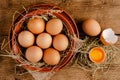 Raw chicken eggs and broken egg shell with yolk on wooden background Royalty Free Stock Photo