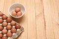 Raw chicken eggs in carton and three eggs in white cup on a light brown wooden background, Top view with copy space Royalty Free Stock Photo