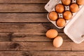 Raw chicken eggs in egg box on wooden background Royalty Free Stock Photo