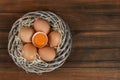 Raw chicken eggs in wicker nest on wooden table, top view Royalty Free Stock Photo