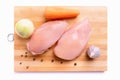 Raw chicken fillet on a cutting board. Chilled chicken breast, carrots and onions top view. Isolated on a white background Royalty Free Stock Photo