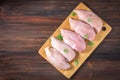 Raw chicken fillets on a cutting board against the background of a wooden table. Meat ingredients for cooking. Empty place for an
