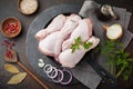 Raw chicken legs on a cast iron pot with spices and herbs on a dark concrete or stone background prepared for cooking. Selective Royalty Free Stock Photo