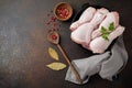 Raw chicken legs on a cast iron pot with spices and herbs on a dark concrete or stone background prepared for cooking. Selective Royalty Free Stock Photo