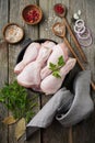 Raw chicken legs on a cast iron pot with spices and herbs on old wooden background prepared for cooking. Selective focus. Top view Royalty Free Stock Photo