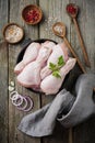 Raw chicken legs on a cast iron pot with spices and herbs on old wooden background prepared for cooking. Selective focus. Top view Royalty Free Stock Photo