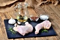 Raw chicken legs on a cutting board with a fresh rosemary, garlic, cumin, jug with oil, pepper and salt on a wooden Royalty Free Stock Photo