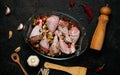 Raw chicken legs and lots of spice in a transparent dish on a black background. Royalty Free Stock Photo