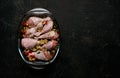 Raw chicken legs and lots of spice in a transparent dish on a black background. Royalty Free Stock Photo