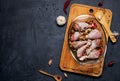 Raw chicken legs and lots of spice in a transparent dish on a dark background. Royalty Free Stock Photo