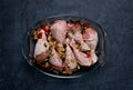 Raw chicken legs and lots of spice in a transparent dish on a dark background. Royalty Free Stock Photo