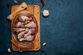 Raw chicken legs and lots of spice in a transparent dish on a dark background. Royalty Free Stock Photo