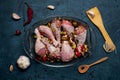 Raw chicken legs and lots of spice in a transparent dish on a dark background. Royalty Free Stock Photo