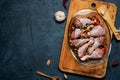 Raw chicken legs and lots of spice in a transparent dish on a dark background. Royalty Free Stock Photo