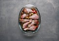 Raw chicken legs and lots of spice in a transparent dish on a grey background. Royalty Free Stock Photo