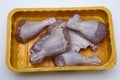 raw chicken legs in a plastic container on a white