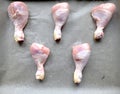 Raw chicken legs prepared for cooking in the oven on the baking pan and backing paper with salt