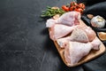 Raw chicken legs with spices and vegetables on a wooden cutting board. Black background. Top view. Copy space Royalty Free Stock Photo