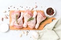 Raw chicken legs with spices on wooden cutting board over white concrete background Royalty Free Stock Photo