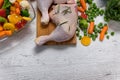 Raw chicken legs from vegetables to a wooden table