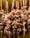Raw chicken marinading on bamboo skewers.
