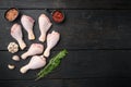 Raw chicken meat fillet, thigh, wings and legs , with seasoning and herbs rosemary and thyme, on black wooden table background, Royalty Free Stock Photo