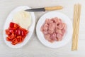 Raw chicken meat, onion, pepper in plates, skewers and knife