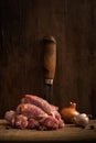 raw chicken necks with onions, garlic and peppercorns on a cutting board on a shabby wooden background. artistic vertical moody Royalty Free Stock Photo