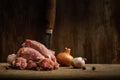 raw chicken necks with onions, garlic and peppercorns on a cutting board on a shabby wooden background. moody meat still life with Royalty Free Stock Photo