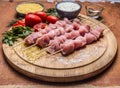 Raw chicken pieces on skewers on a chopping board with herbs vegetables sauce on wooden background close up Royalty Free Stock Photo