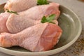 Raw chicken in a plate. Marinated meat, with oregano, herbs and paprika. Raw chicken legs, step by step cooking. Close-up, gray