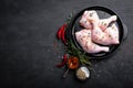 Raw chicken quarters, legs in a pan on a dark background