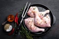 Raw chicken quarters, legs in a pan on a dark background