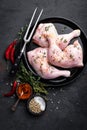 Raw chicken quarters, legs in a pan on a dark background