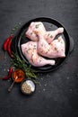 Raw chicken quarters, legs in a pan on a dark background