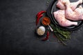 Raw chicken quarters, legs in a pan on a dark background