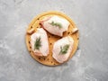 Raw chicken thighs on cutting board with ingredients for cooking at grey concrete kitchen table. Top view with copy space Royalty Free Stock Photo