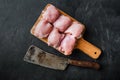 Raw chicken thighs with meat cleaver, on black background, top view